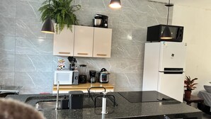 Una cocina moderna con salpicadero de mármol, microondas, cafetera, licuadora y refrigerador.