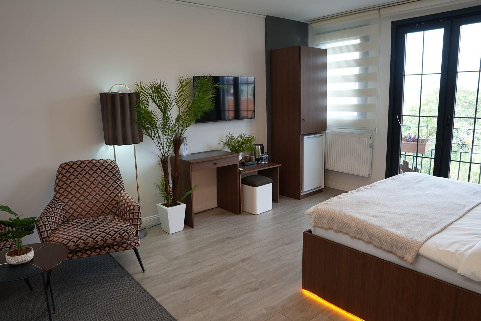 A modern bedroom with a bed, a desk, a chair, and a TV.
