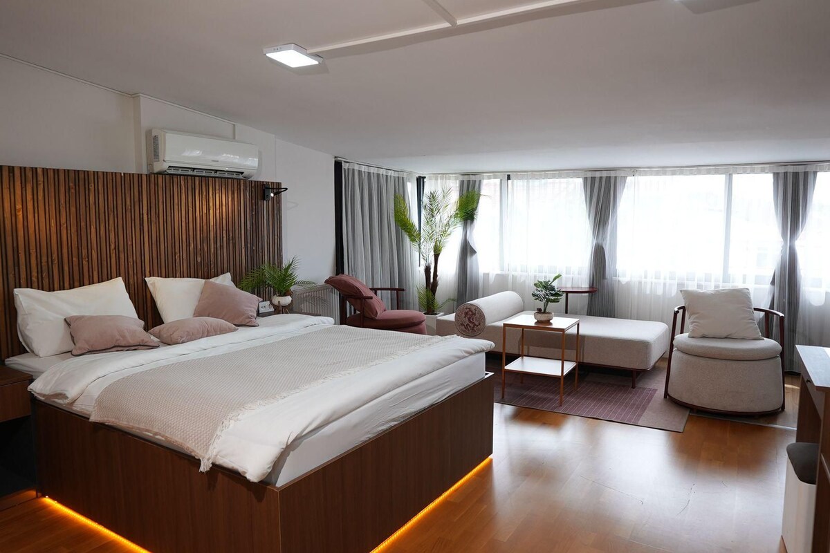 Un dormitorio moderno con una cama grande, un espacio de descanso con una mesa y una silla.