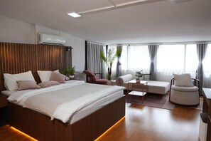 A modern bedroom with a large bed, a sitting area with a table, and a chair. - Vicolo Moda kadıköy (İstanbul)