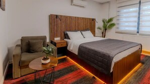 A hotel room with a bed, a sofa, a small table with a plant, and a window with blinds. - Vicolo Moda kadıköy (İstanbul)