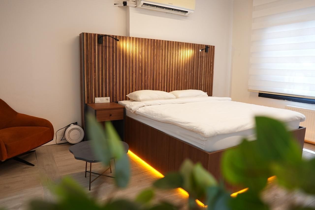 Une chambre à coucher moderne avec une tête de lit en bois, une table de chevet, une chaise et une lampe de chevet.