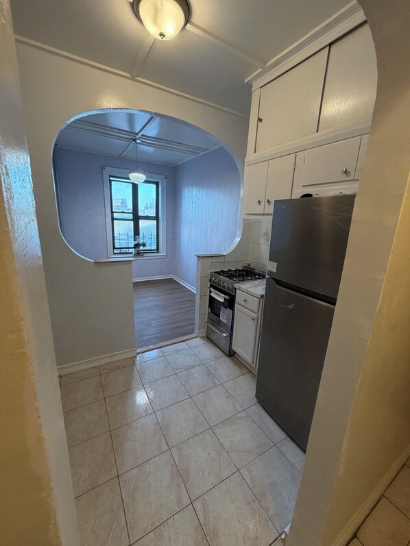 A kitchen with white cabinets, a stainless steel refrigerator, and a gas stove.