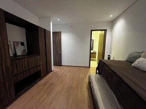 Ein Schlafzimmer mit einem Bett, einem Kleiderschrank und einer Tür zu einem weiteren Raum.