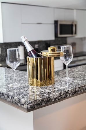 Una encimera de cocina con un cubo dorado para champán, dos copas y un microondas.