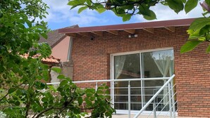 A brick building with a large window and a white railing.