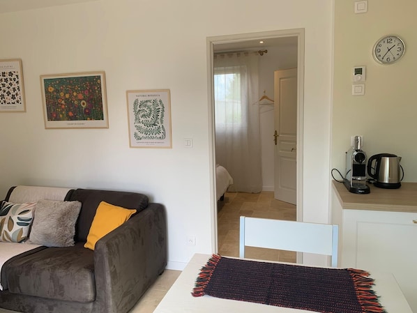 A living room with a sofa, a coffee maker, and a kettle on the counter.