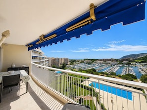 Un balcon avec vue sur un port de plaisance, une piscine et les bĂątiments environnants.