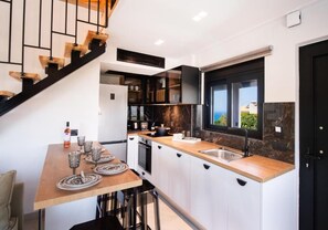Una cocina moderna con una mesa de madera, taburetes de bar, horno empotrado y un ventanal grande.
