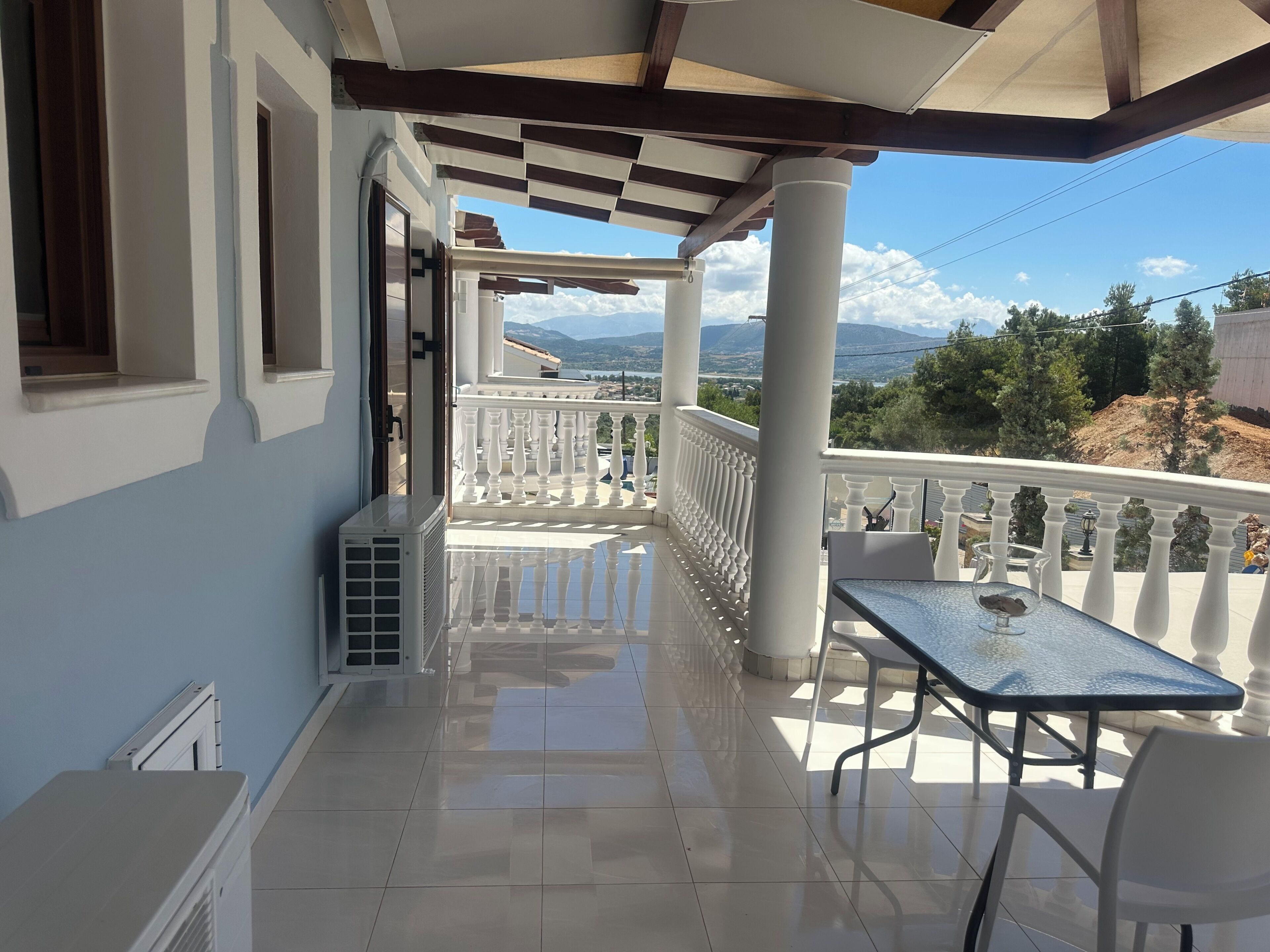 A balcony with a tiled floor, white railings, and a table with chairs.