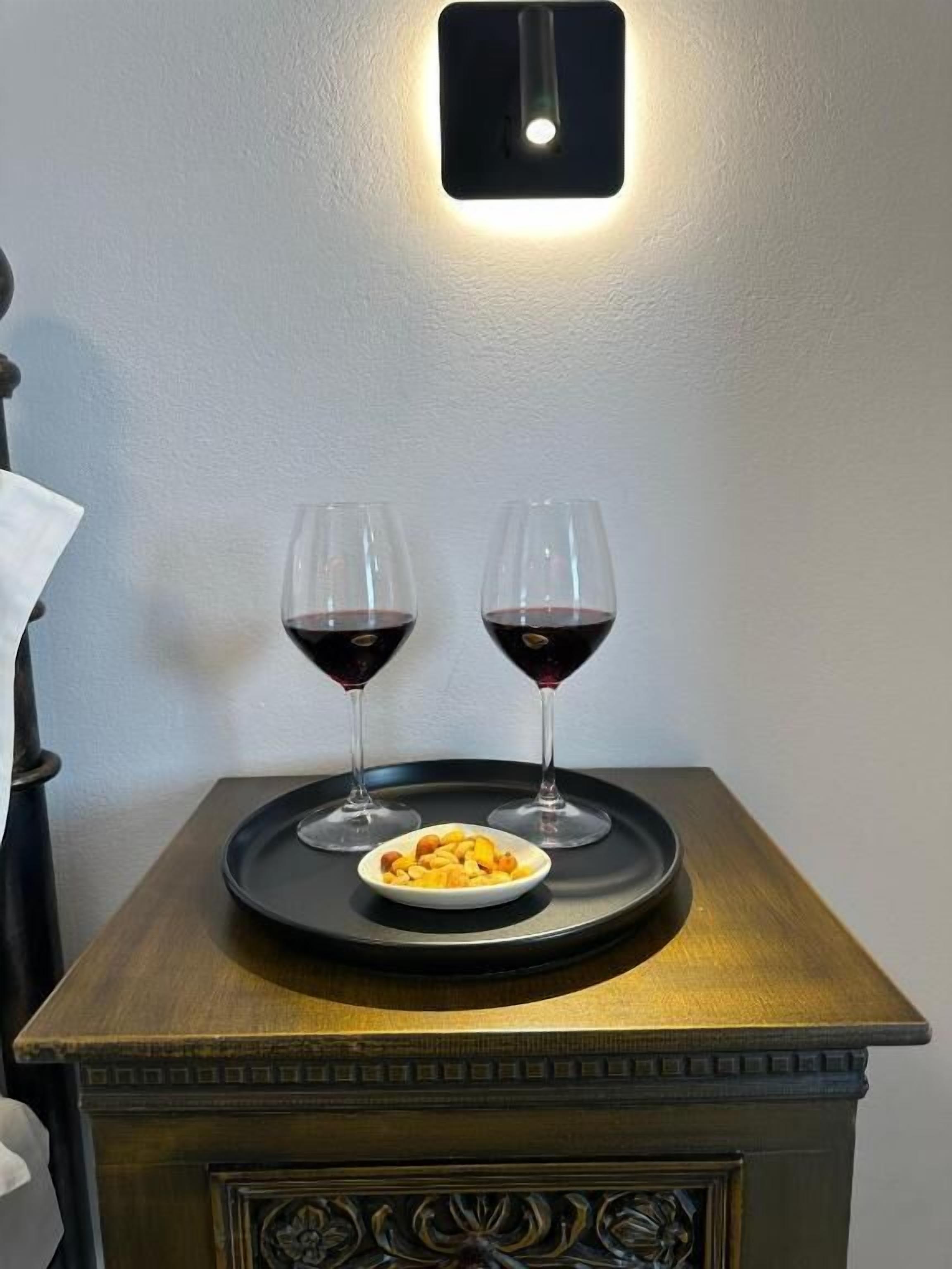 Une table en bois sur laquelle sont posés deux verres à vin et un bol de nourriture.