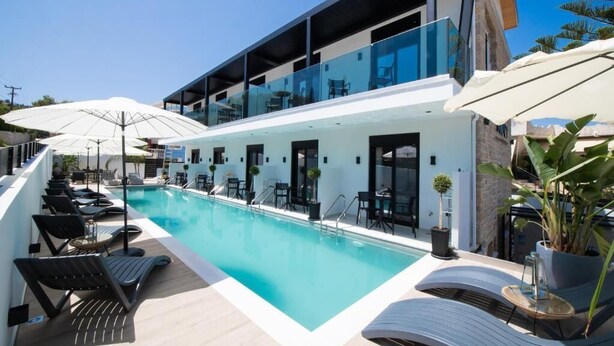 A modern hotel with a pool, outdoor seating, and a glass-enclosed upper level.