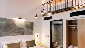 A bedroom with a large bed, a wooden ceiling, a balcony, and a wardrobe.