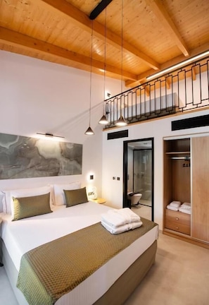 Un dormitorio con una cama grande, techo de madera, balcón y armario.