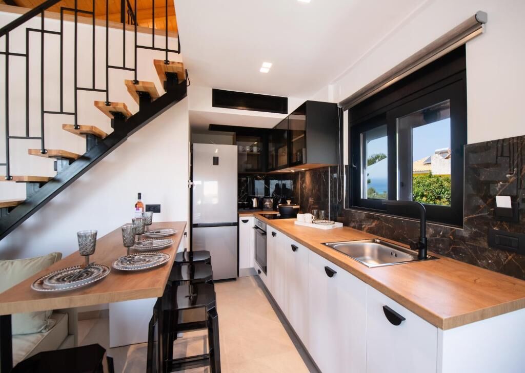 A modern kitchen with a wooden island, a built-in oven, and a large window.