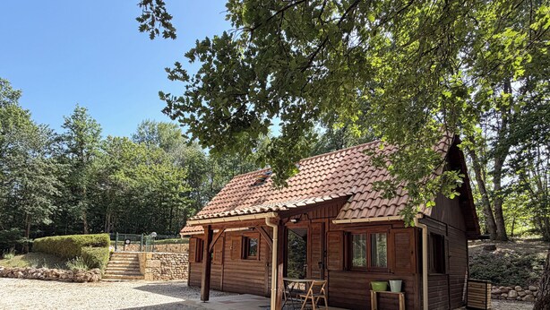 Eine Holzhütte mit einem Ziegeldach, umgeben von Bäumen und Kies.