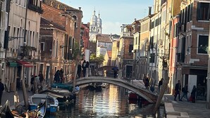 A canal with buildings on either side, a bridge, and a tower in the distance.