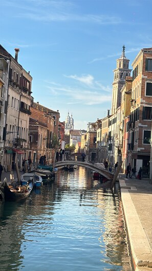 A canal with buildings on either side, a bridge, and a tower in the distance. - Vrbo Property (Venezia)
