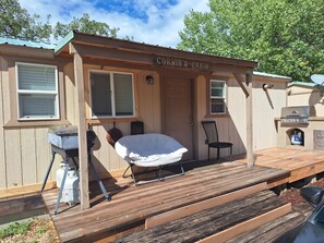 Eine Hütte namens 'Corwin's Cabin' mit überdachter Veranda, Grill und Stuhl.