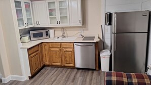 A compact kitchen with white cabinets, a microwave, a dishwasher, and a refrigerator. - Beautiful 1-bedroom cabin with AC in charming Glendale (Glendale)