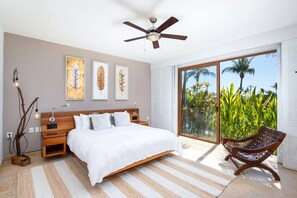 Ein Schlafzimmer mit Bett, Deckenventilator, Nachttisch, Lampe und Stuhl.