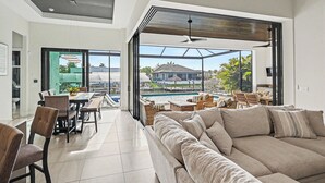 Sala moderna com um sofá grande, área de jantar e vista para uma piscina.