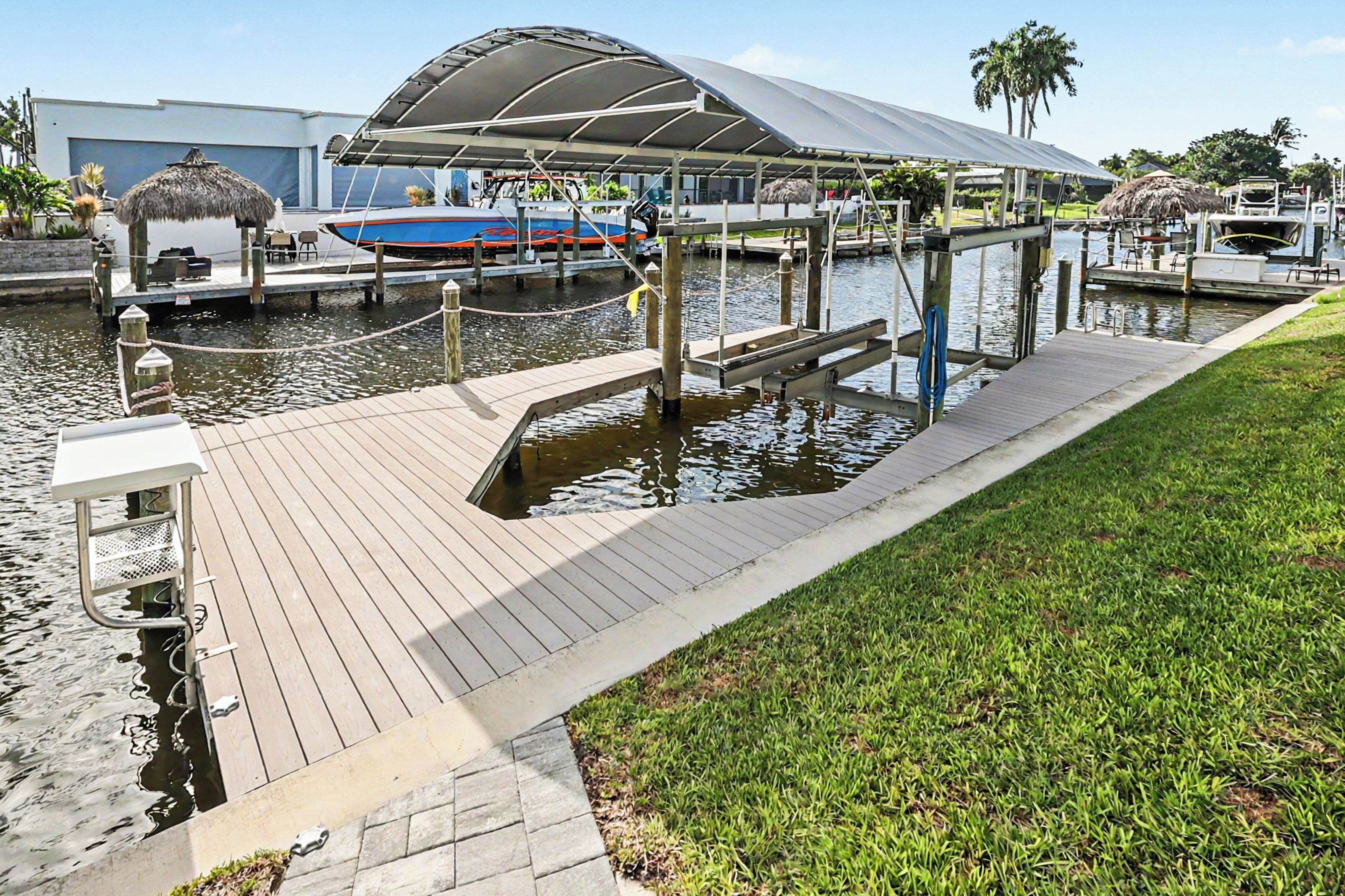 Eine Uferpromenade mit einem überdachten Sitzbereich, einem Boot und einem Gebäude mit einer großen Markise.