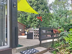 A patio area with a bench, a yellow umbrella, and potted plants. - Les Pins by Interhome (Lacanau)
