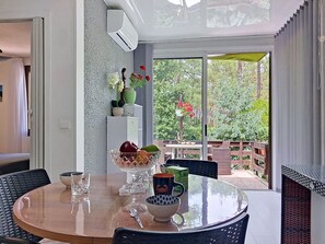 Ein Essbereich mit einem runden Tisch, Stühlen, einer Obstschale, einer Kaffeetasse und einem Blumentopf.