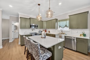 A modern kitchen with green cabinets, a central island, and pendant lighting. - Napping Turtle a serene 4-bedroom +bonus room. with AC in charming Springfield (Springfield)