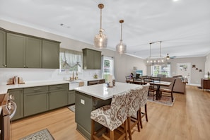 A spacious kitchen with a central island, green cabinets, and pendant lighting. - Napping Turtle a serene 4-bedroom +bonus room. with AC in charming Springfield (Springfield)