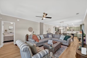 A modern living room with a sectional sofa, a coffee table, and a dining area with a chandelier. - Napping Turtle a serene 4-bedroom +bonus room. with AC in charming Springfield (Springfield)