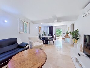 Ein modernes Wohnzimmer mit einer Couch, einem Esstisch, Stühlen und einem Fernseher.