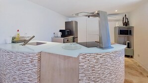 A modern kitchen with a central island, built-in appliances, and a minimalist design. - Bas de villa Anémones by Interhome (Bormes-les-Mimosas)