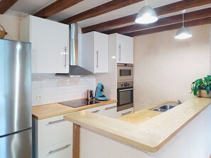 Eine moderne Küche mit Edelstahlgeräten, Holz Arbeitsplatten und Pendelleuchten.