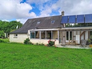 Ein Haus mit überdachter Terrasse, Solaranlage und Garten.