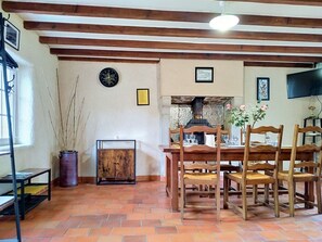 Ein Essbereich mit Holztisch und Stühlen, einer Uhr an der Wand und einem Kamin.