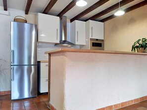 A kitchen with a stainless steel refrigerator, white cabinets, a built-in oven, and a wooden countertop. - L'ancienne Ferme by Interhome (Lestre)