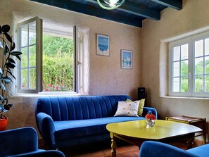 A room with a blue sofa, a yellow table, and a window with a view of greenery. - L'ancienne Ferme by Interhome (Lestre)