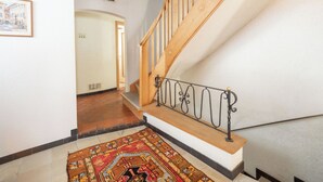 A staircase with a wooden handrail and a metal balustrade, leading to an upper floor.