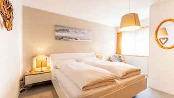 A modern hotel room with a large bed, bedside lamps, a wall-mounted picture, a window with curtains, and a circular wall decoration.