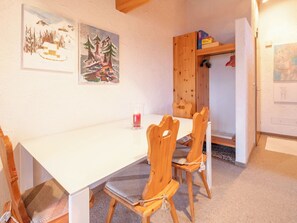 Ein Essbereich mit einem weißen Tisch, Holzstühlen, einer Kerze auf dem Tisch und Bildern an der Wand.