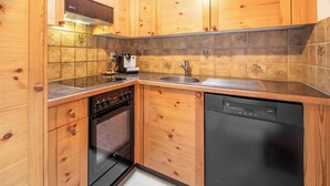 Une cuisine avec des meubles en bois, une cuisinière, un four, un lave-vaisselle et un dosseret carrelé.