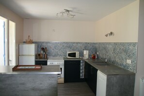 A compact kitchen with a refrigerator, microwave, stove, and sink. - Quiet vacation home for families (Piriac-sur-Mer)