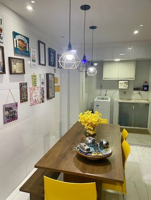 A dining area with a wooden table, yellow chairs, and a vase of yellow flowers.