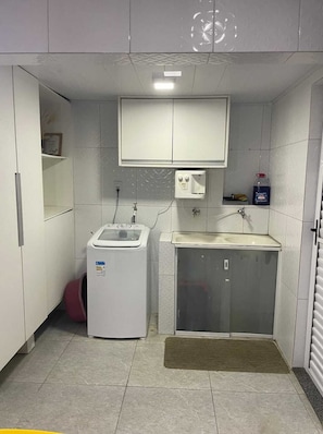 A compact bathroom with a washing machine, a sink, and a cabinet. - Casa da Lu (Salvador)