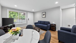 A modern living room with a sofa, TV, and dining area. - King Bed-Stadium District Getaway (Tacoma)