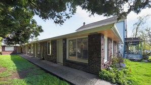 A row of brick buildings with large windows, a concrete pathway, and a grassy area with trees. - King Bed-Stadium District Getaway (Tacoma)