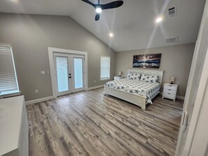 A bedroom with a bed, nightstands, a ceiling fan, and a large window. - Black-Water River Retreat! to this Luxurious 3-bedroom 3.5 bath house (Milton)