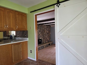 Una cocina con armarios de madera, una pared de piedra y una puerta blanca.